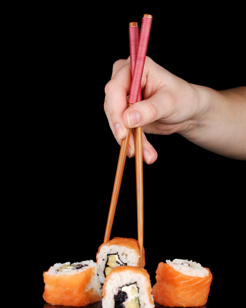 holding-roll-with-chopsticks-isolated-black holding-roll-with-chopsticks-isolated-black
